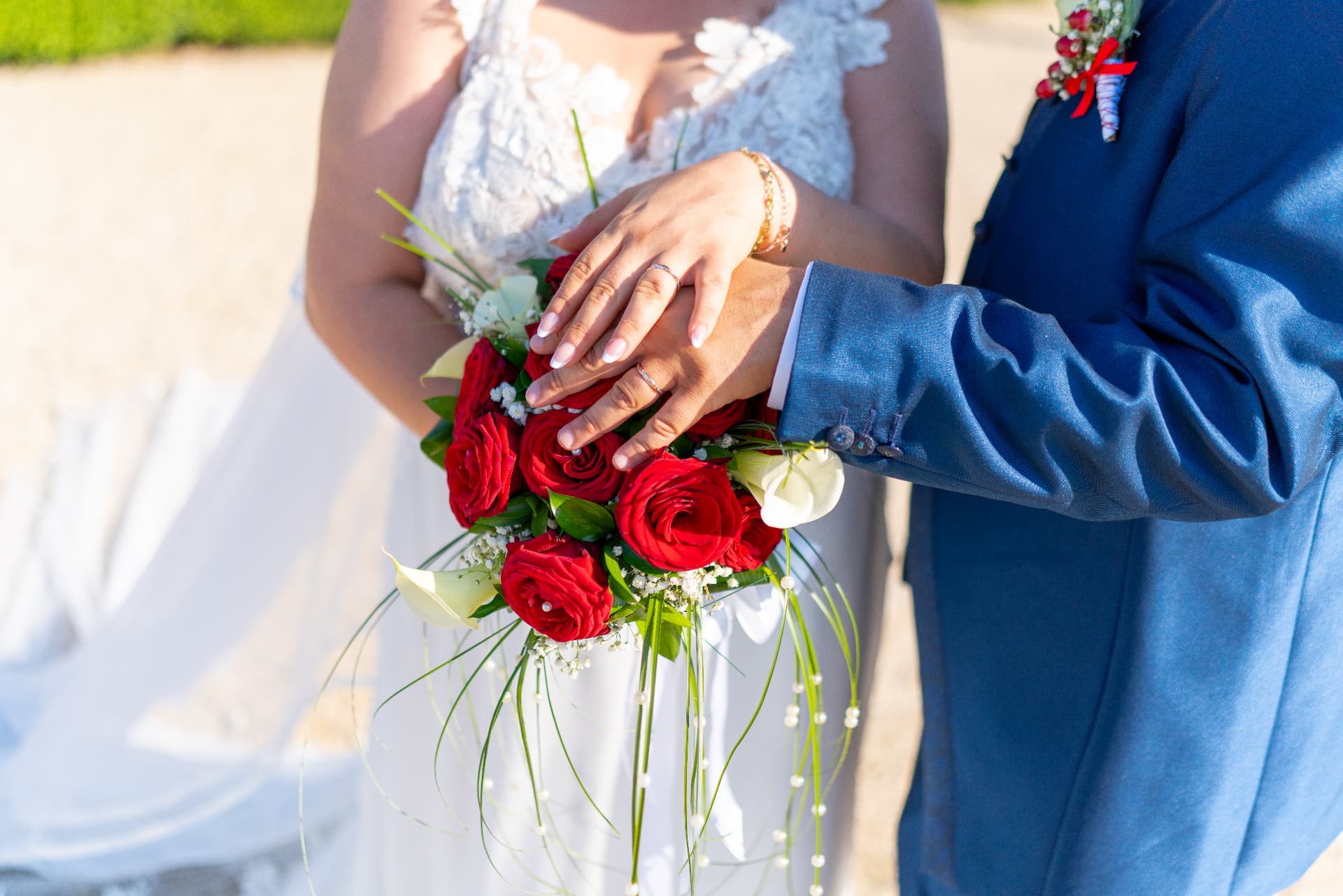 Mani degli sposi sul bouquet di rose rosse
